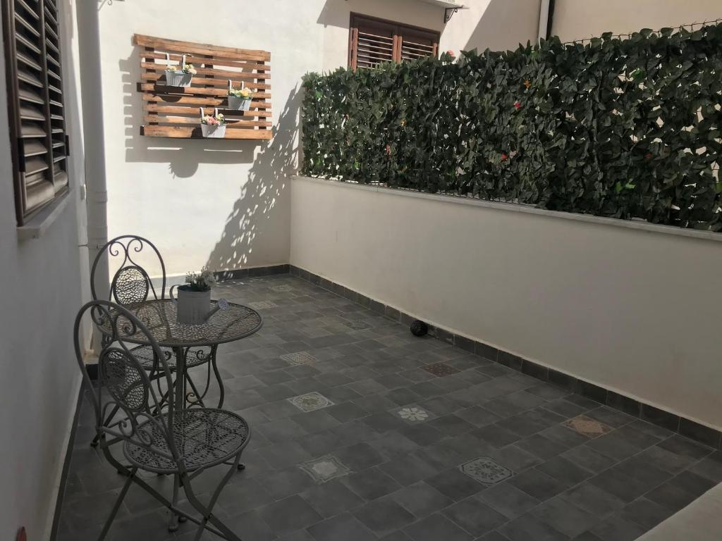 a patio with two chairs and a table and a hedge at Il mio posto ai Quattro Canti - Centro storico Palermo in Palermo
