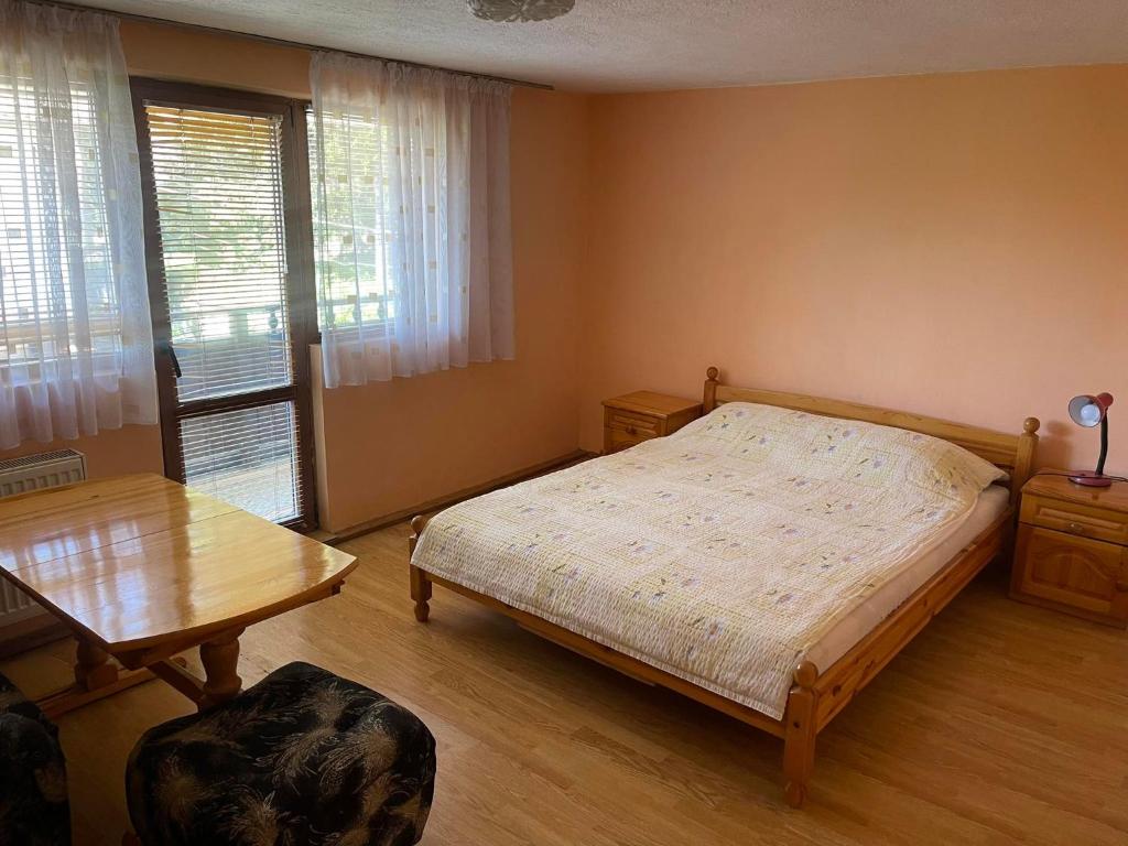 1 dormitorio con cama y mesa de madera en Вила Мечта, en Tryavna