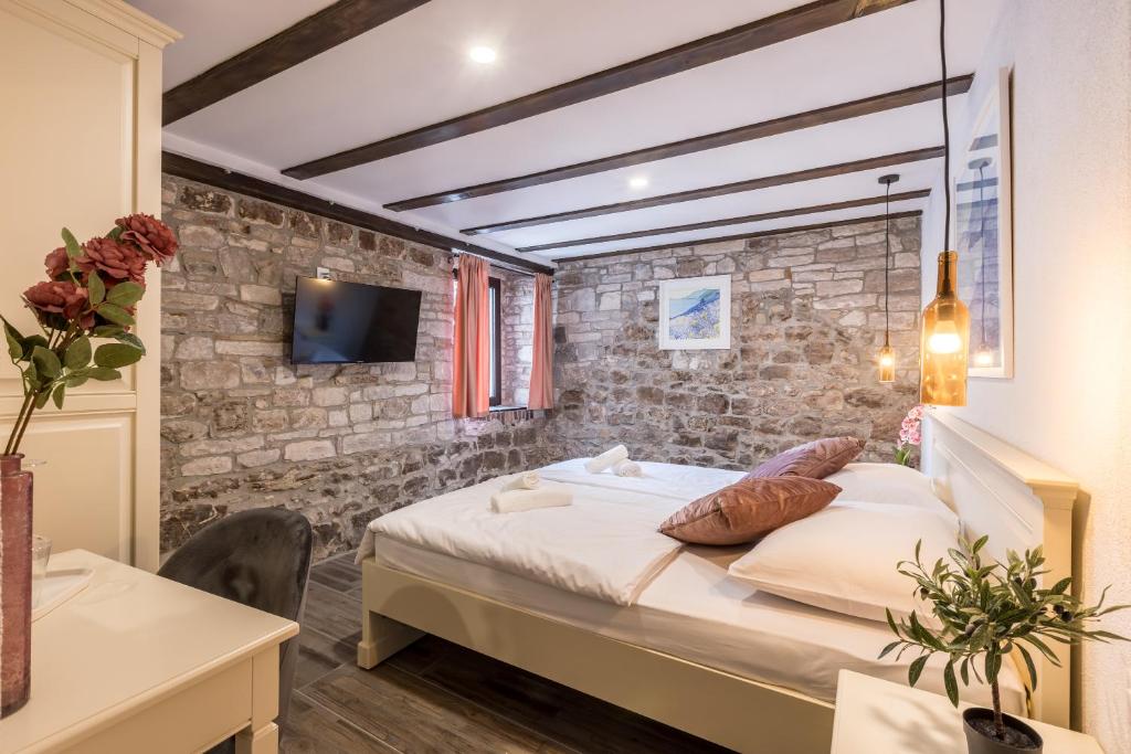 a bedroom with a bed and a stone wall at Luxury B&B Rooms Matusko in Split
