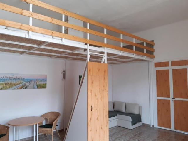 a loft bed in a room with a bed and a table at 20 Bakancs Apartman in Esztergom