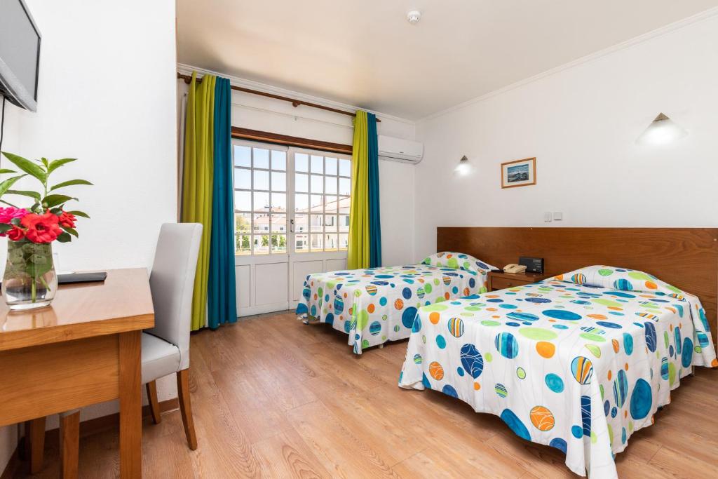 een slaapkamer met 2 bedden, een bureau en een tafel bij Hotel Azul Praia in Altura