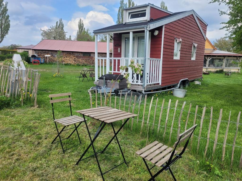 a red house with a table and chairs in a yard at Tiny House in Schönbeck
