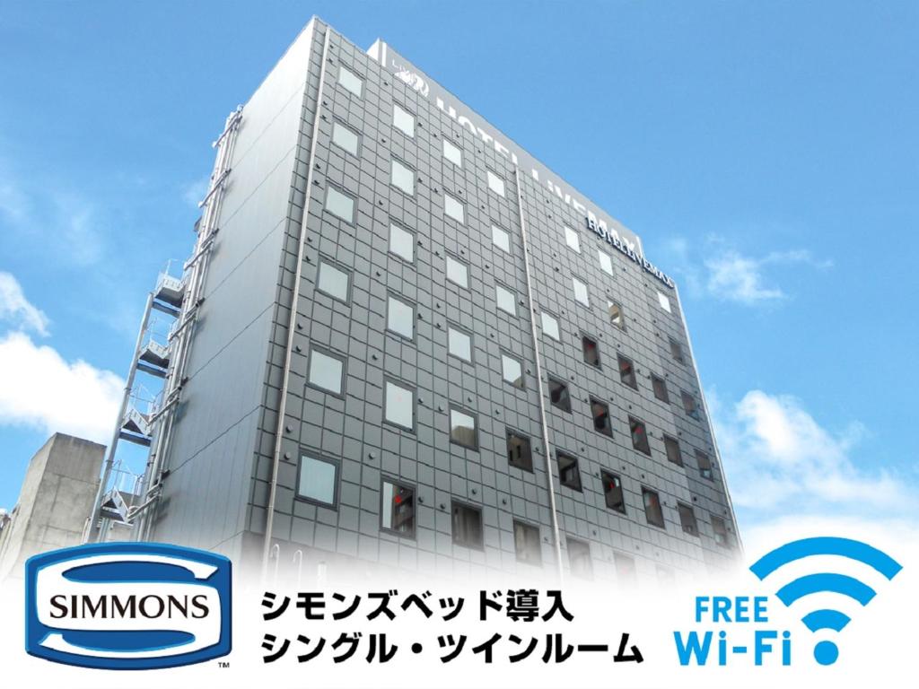 a tall building with a sign in front of it at HOTEL LiVEMAX Numazu Ekimae Hotel in Numazu