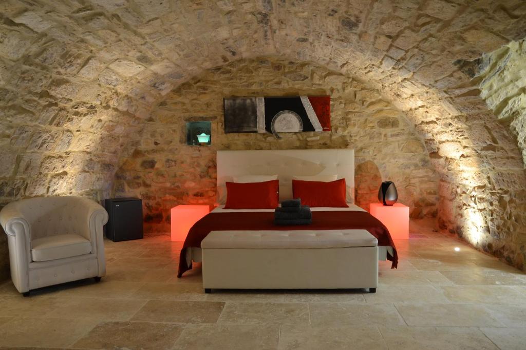 a bedroom with a bed and a chair in a stone tunnel at Chambre d'hôte romantique avec SPA privatif domaine les nuits envôutées - Vézénobres in Vézénobres
