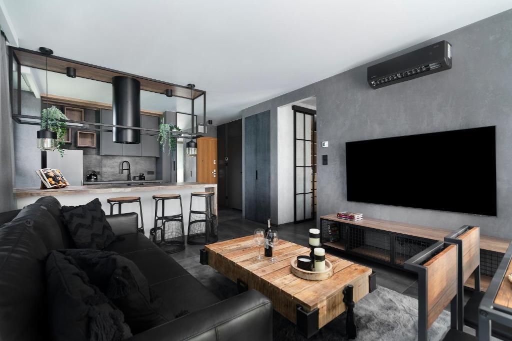 a living room with a black couch and a tv at Easy Rent Apartments - City Rest, Basen & SPA, Centrum Free Parking 24h Check-in in Lublin