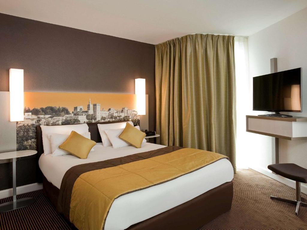 a hotel room with a large bed and a television at Mercure Avignon Centre Palais des Papes in Avignon