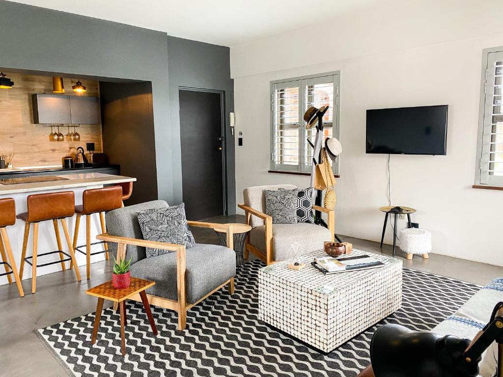 Il comprend un salon avec un canapé et des chaises ainsi qu'une cuisine. dans l'établissement Stay On Main Plett - Contemporary 2-Bedroom Apartment, à Plettenberg Bay