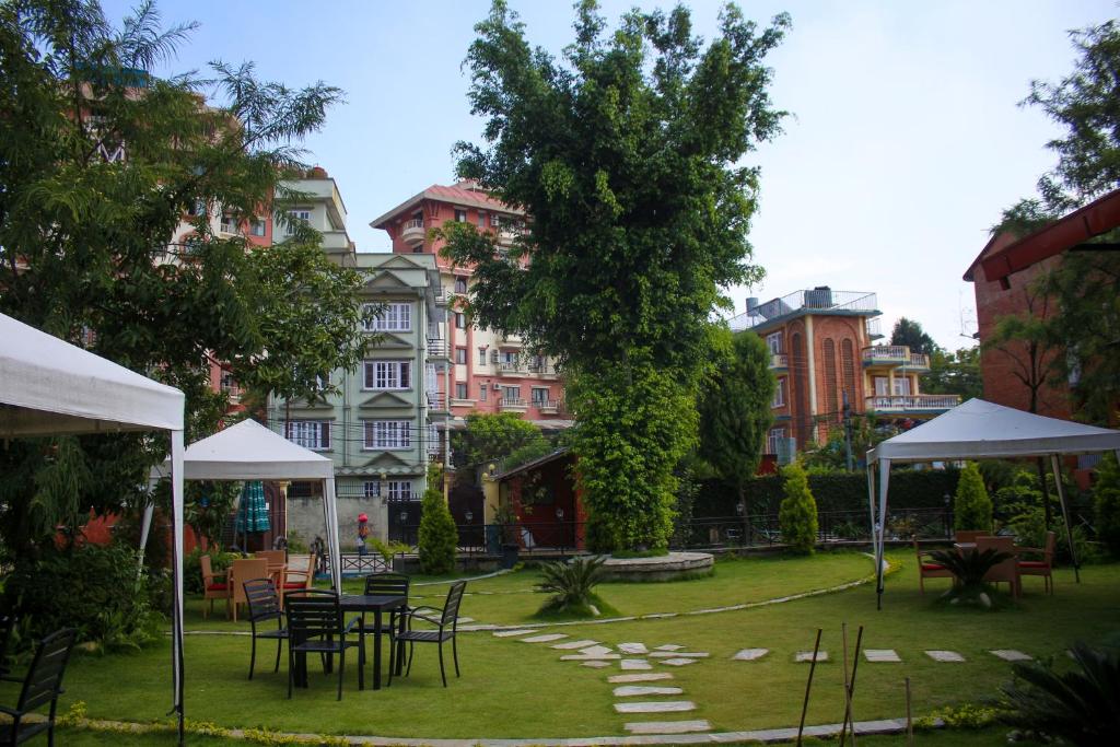 um jardim com mesas e cadeiras em frente aos edifícios em Sampada Garden Resort em Kathmandu