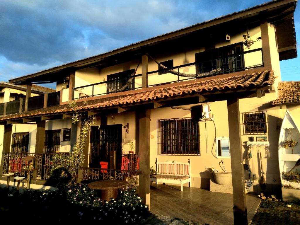 ein Haus mit einem Balkon und einer Bank davor in der Unterkunft Pousada Praia do Calixto in São Francisco do Sul