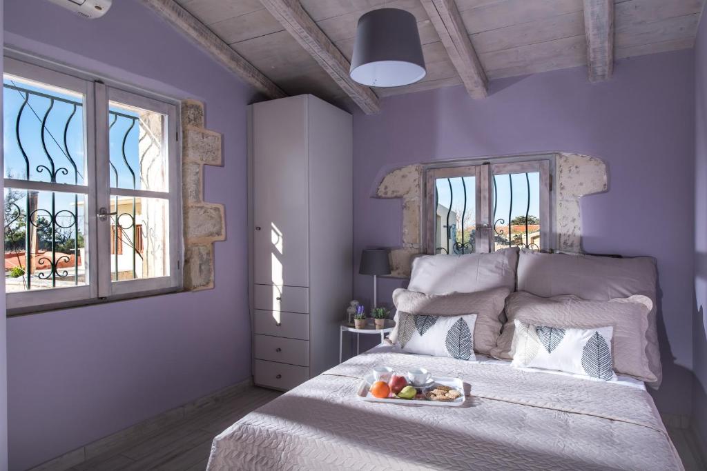a purple bedroom with a bed with a tray of fruit on it at Villa Maris in Melissourgákion