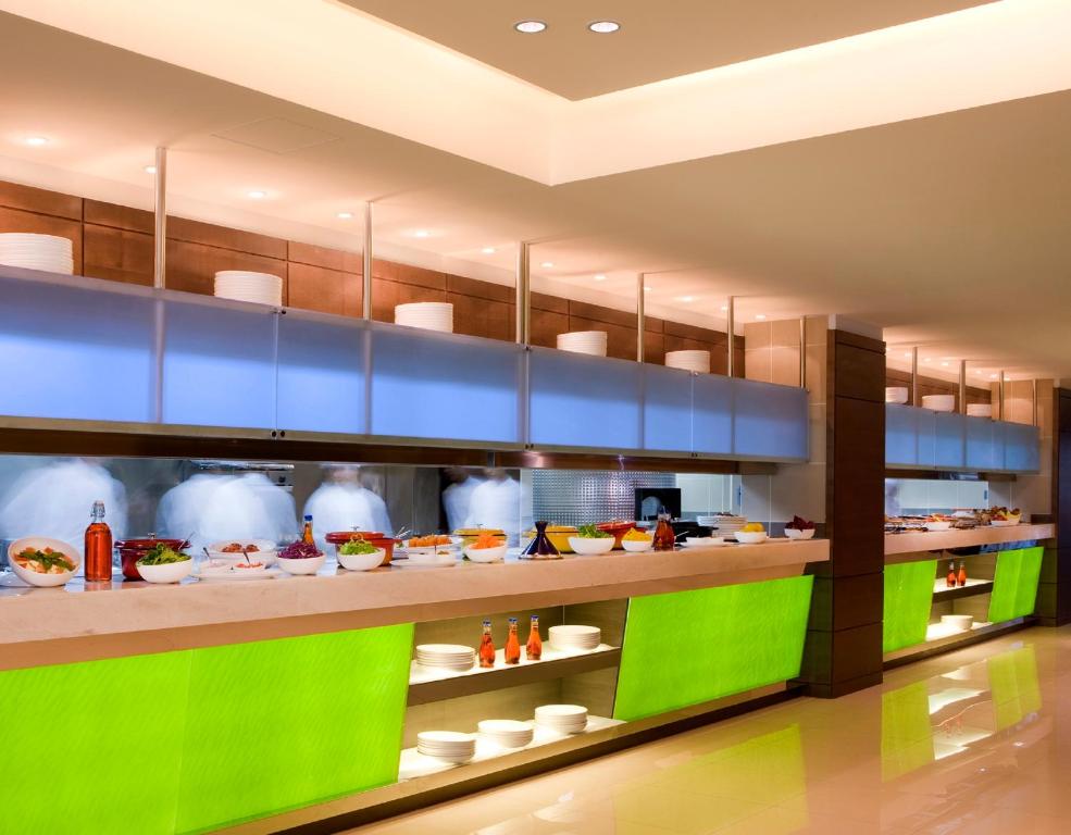 a kitchen with green and blue shelves with food at Traders Hotel, Abu Dhabi in Abu Dhabi