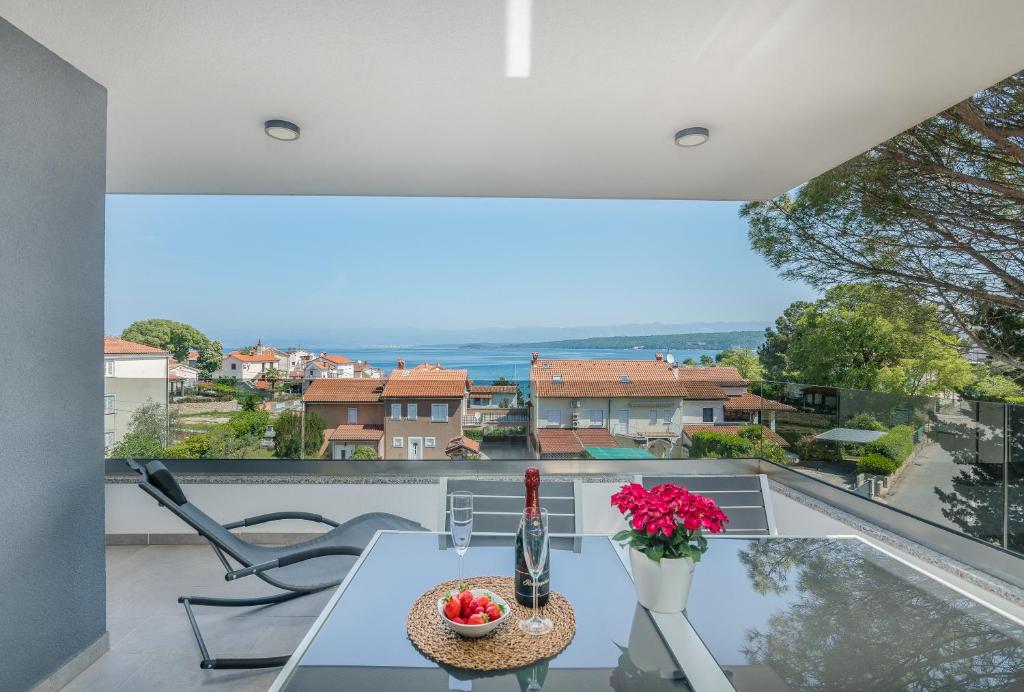 een uitzicht vanaf het balkon van een huis met een tafel en bloemen bij Modern Apartments Elle Malinska in Vantačići