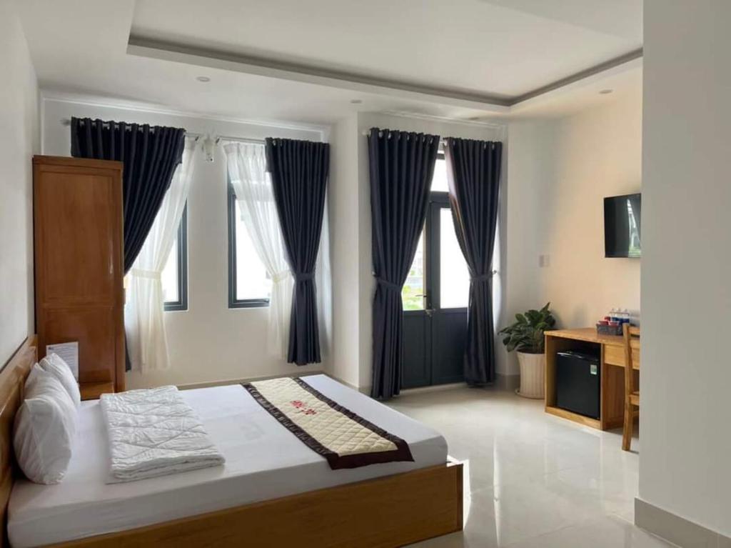 um quarto com uma cama grande e cortinas azuis em ĐỨC THẠNH HOTEL em Rạch Giá