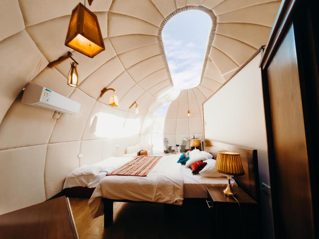 a room with a bed with a large window at Rum Oasis Luxury Camp in Wadi Rum