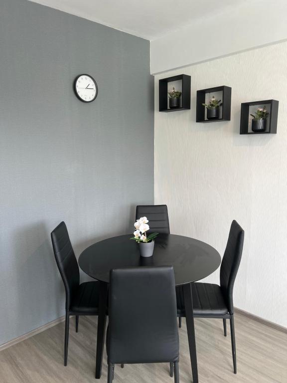 a dining room table with chairs and a clock on the wall at Kemi CITY III near snowcastle, 2 rooms , kitchen , glazed balcony, FREE private parking in Kemi