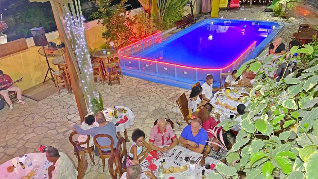 Hôtel Restaurant Coco Lodge Majunga في ماهاجانجا: مجموعة من الناس يجلسون على الطاولات أمام المسبح