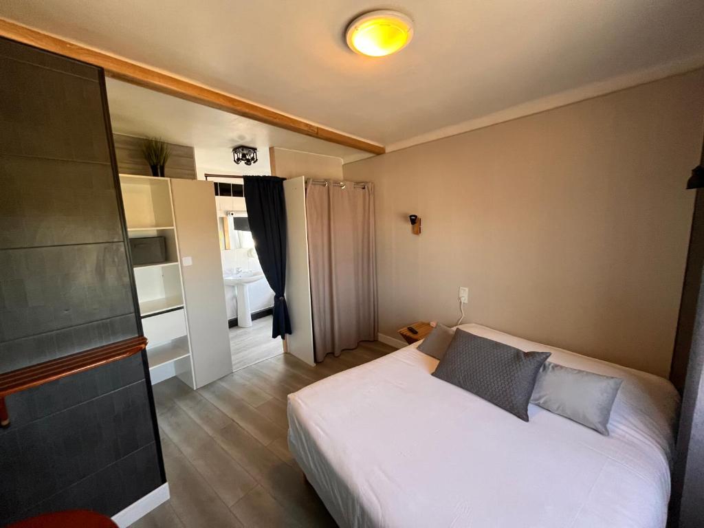 een slaapkamer met een wit bed in een kamer bij Hôtel des îles in Theix