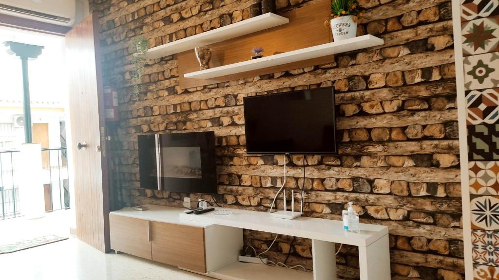 a living room with a tv on a brick wall at Casa el Anden 11 in El Bosque