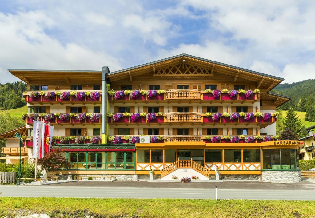 un gran edificio con flores en los balcones en Hotel Barbarahof Saalbach en Saalbach Hinterglemm