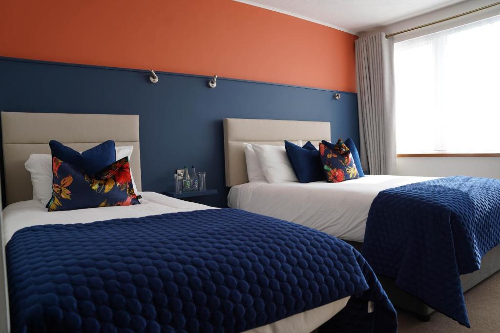 two beds in a bedroom with blue and orange walls at Alcock & Brown Hotel in Clifden