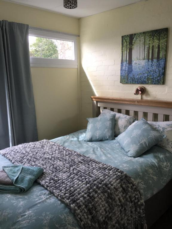 a bedroom with a bed with pillows and a window at Pine Song Chalet in Roch