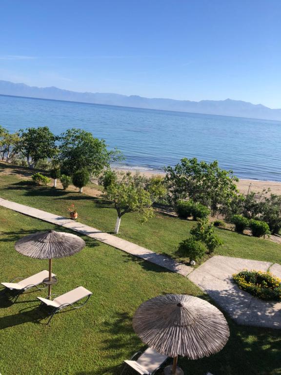 a lawn with chairs and umbrellas next to the ocean at Villa Panorama Astrakeri Beach in Astrakeri