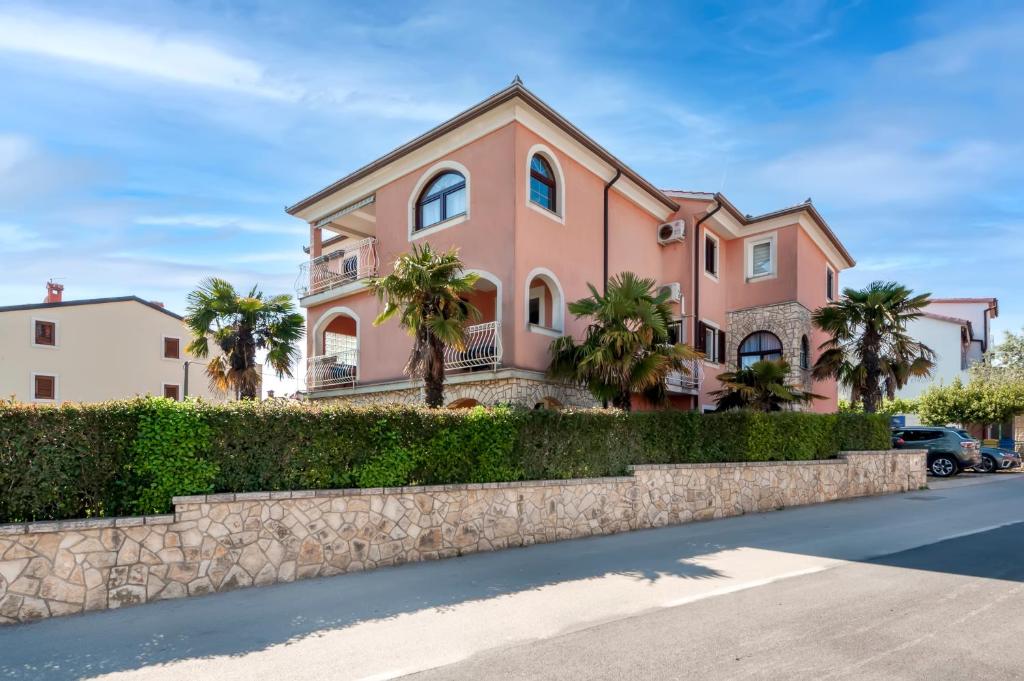 ein rosafarbenes Haus mit Palmen davor in der Unterkunft Apartments Villa Istria Rovinj in Rovinj