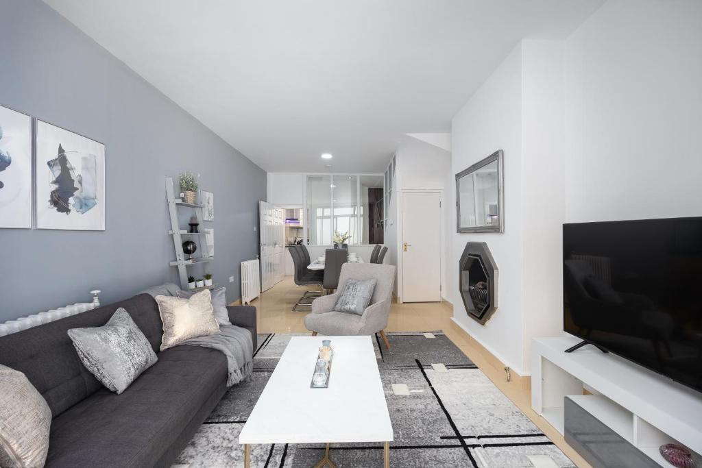 ein Wohnzimmer mit einem Sofa und einem TV in der Unterkunft Spacious 4 Bedroom House next to Kensington Palace in London