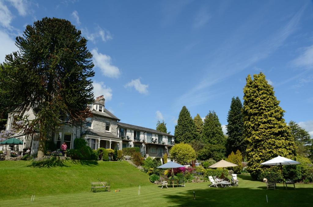 ein großes Haus mit einem Hof mit Tischen und Sonnenschirmen in der Unterkunft Clare House Hotel in Grange Over Sands