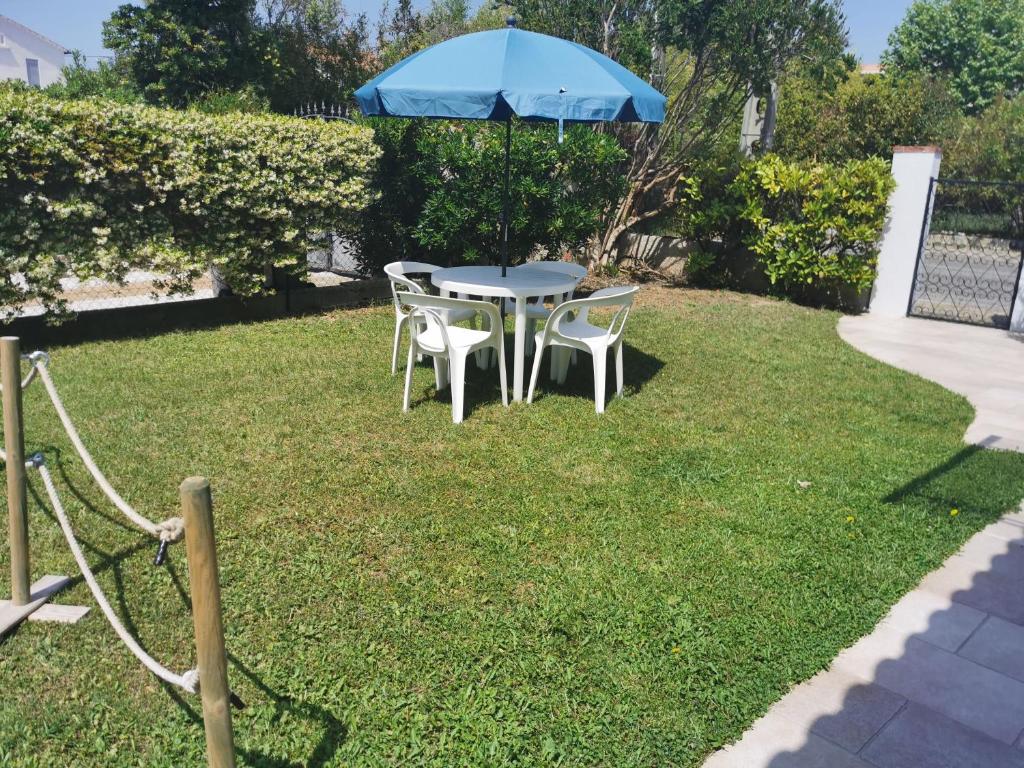 une table et des chaises avec un parasol dans l'herbe dans l'établissement Au clair de la Dune, à Saint-Cyr-sur-Mer