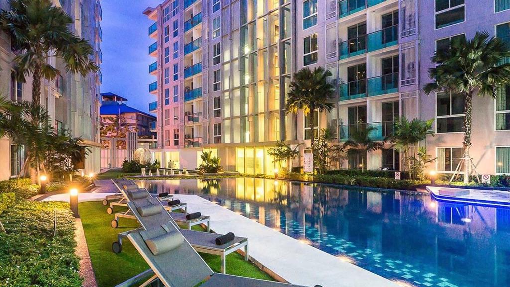 a swimming pool with lounge chairs next to a building at City Center Residence Kim in Pattaya Central