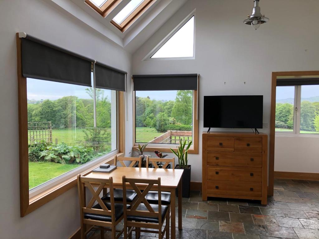 a dining room with a table and a tv and windows at The Cottage, near Glasgow Milngavie in Milngavie