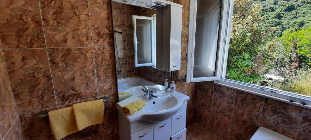 łazienka z umywalką, lustrem i oknem w obiekcie Apartments Lampalo w mieście Okuklje