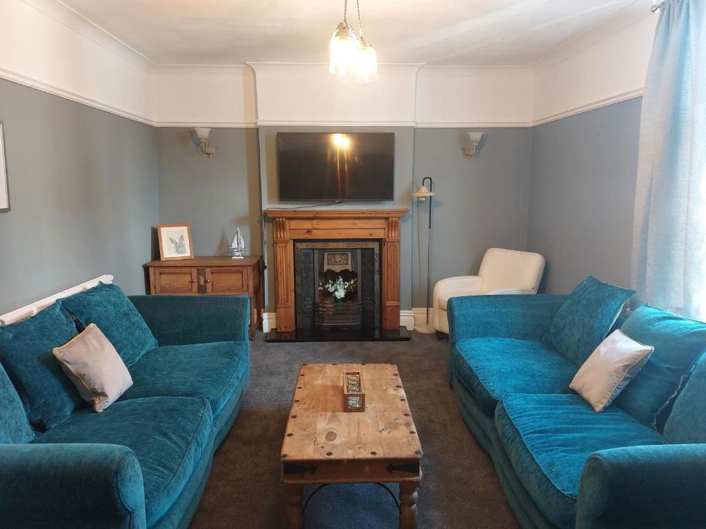 a living room with blue couches and a tv at Llandudno apartment, quirky pub with tropical beer garden in Llandudno