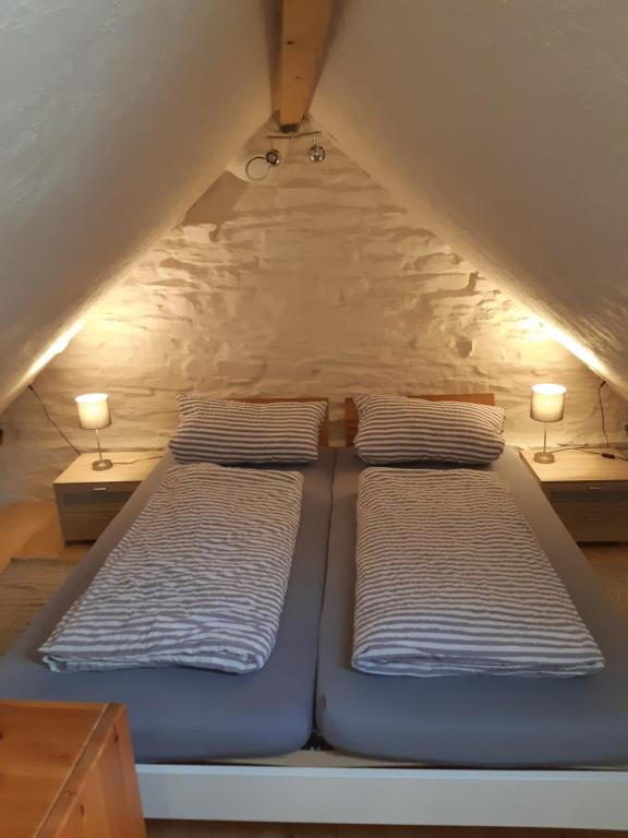 2 Betten in einem Dachzimmer mit 2 Lampen in der Unterkunft Ferienwohnung Fritzer in Ellenz-Poltersdorf