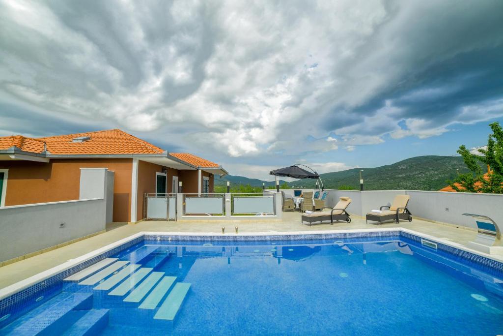 a swimming pool with a patio and a house at Luxury Villa Rebecca in Gornji Muć