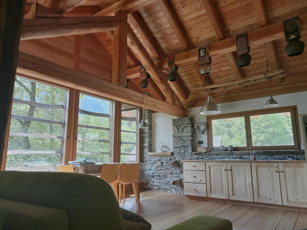 una cucina con soffitti in legno, tavolo e sedie di Baita del noce a Mollia
