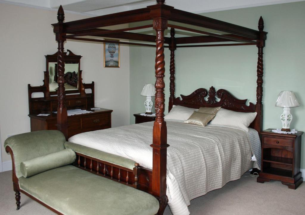 a bedroom with a canopy bed and a chair at Penralley House B&B in Rhayader