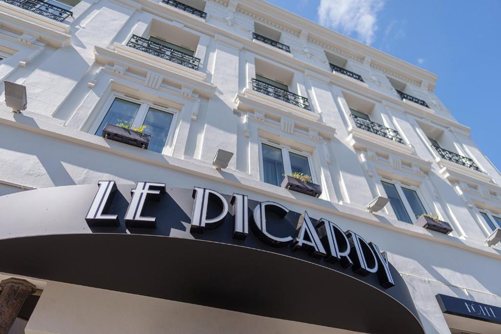 un gran edificio blanco con un cartel. en Hôtel Le Picardy en Saint-Quentin