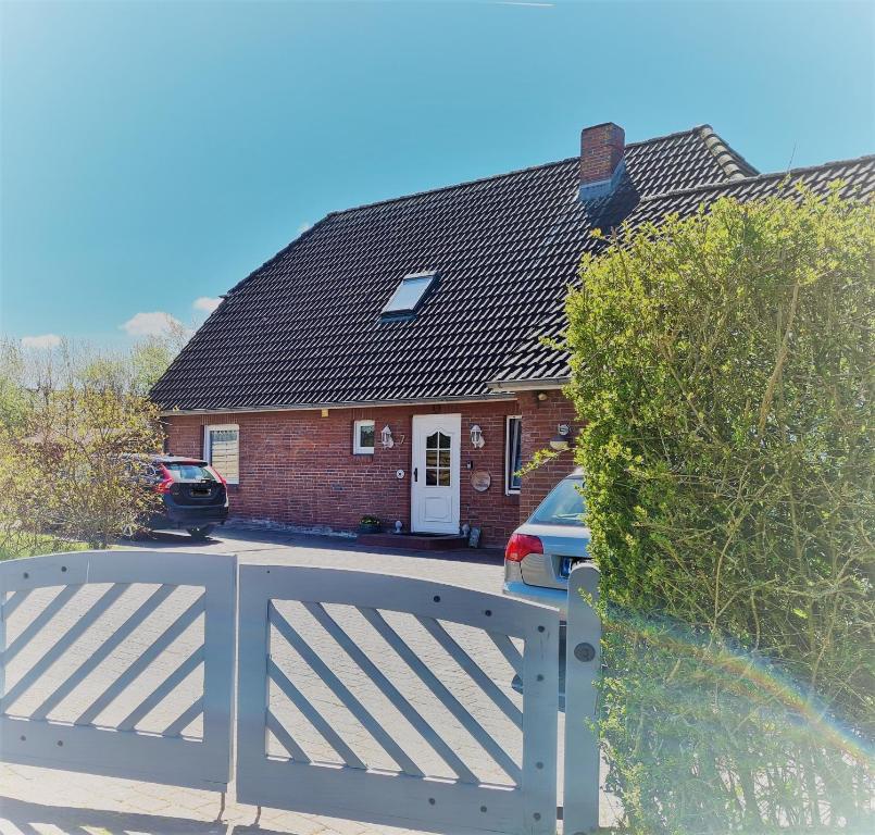 une maison avec une clôture blanche devant elle dans l'établissement Ferienhaus Käthchen am Deich vor den Toren von Sylt, à Emmelsbüll-Horsbüll