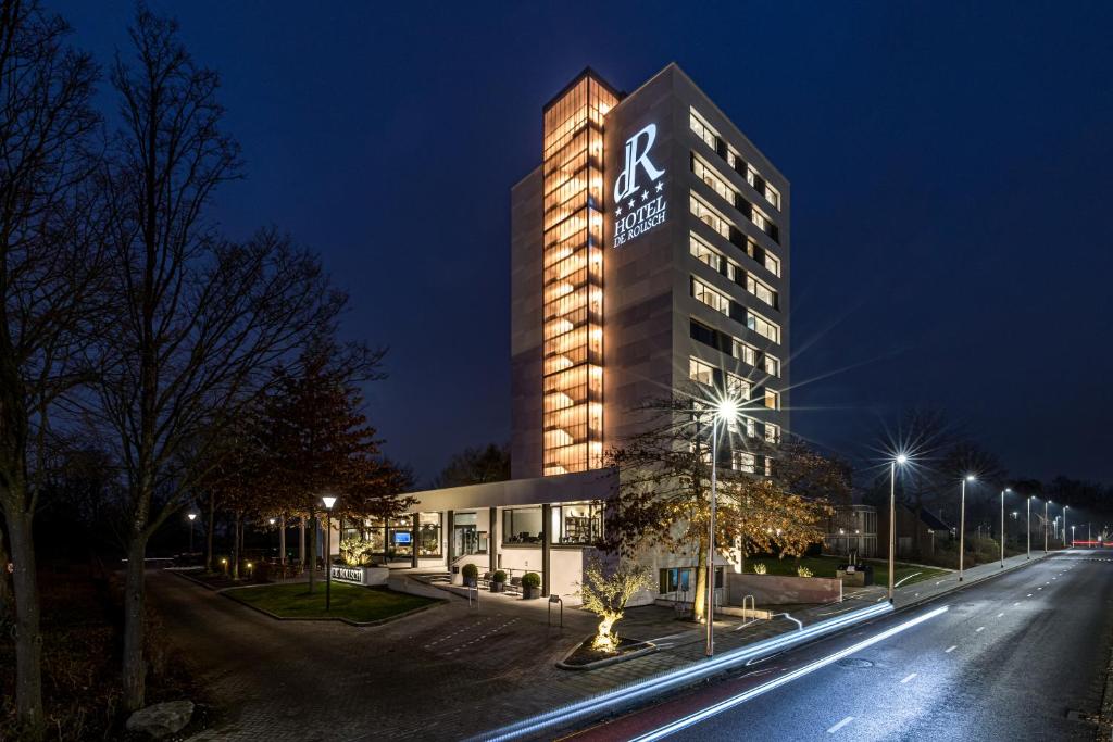 a building with a sign on the side of it at night at Hotel de Rousch in Heerlen