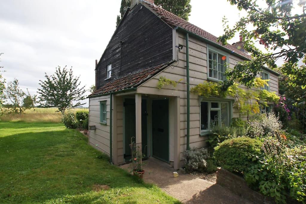 uma pequena casa com uma porta verde num quintal em Cozy cottage overlooking fields, Upwell em Upwell