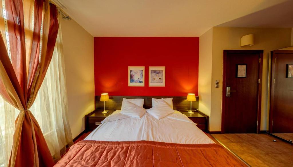 a bedroom with a bed with a red wall at Hotel FAMIL - adults only in Bansko