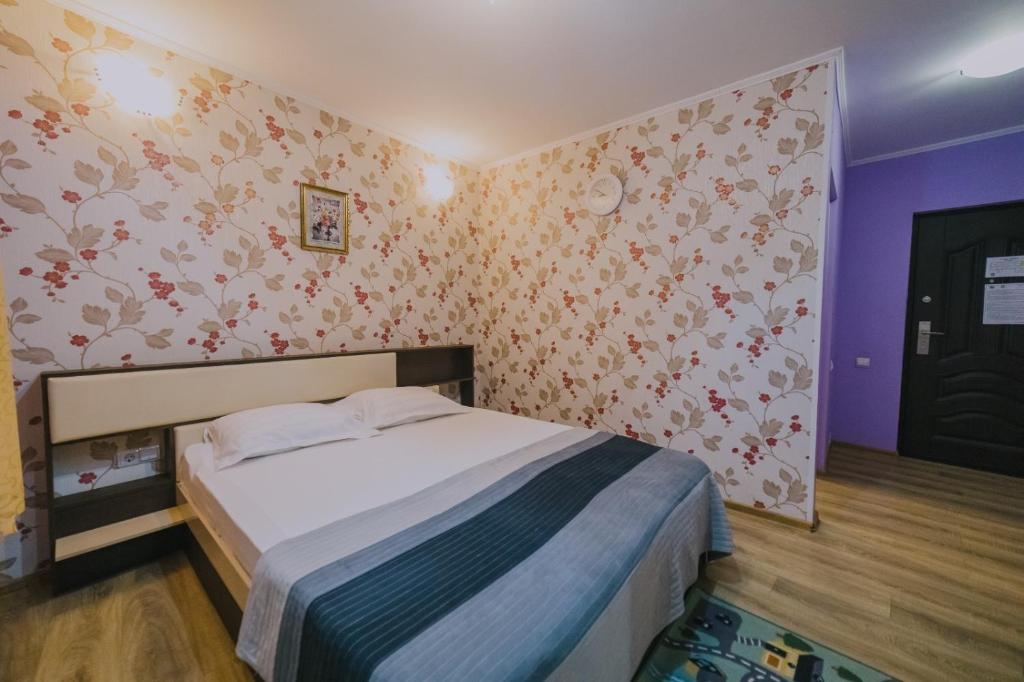 a small bedroom with a bed and floral wallpaper at Hostel Denisa in Buzau