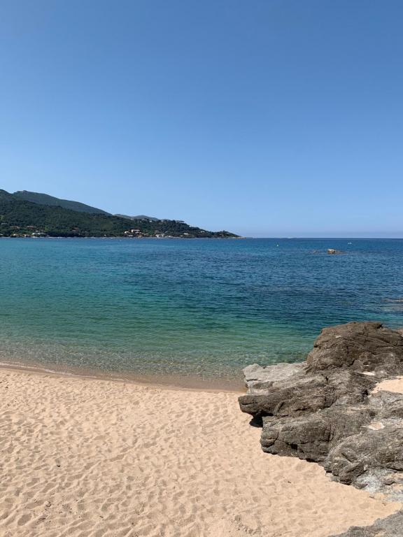 une plage avec des rochers et l'océan par temps clair dans l'établissement Résidence du Parc de la Liscia, à Calcatoggio