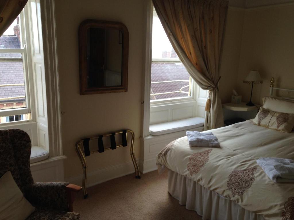 a bedroom with a bed and two windows at Kirkgate House Hotel in Thirsk