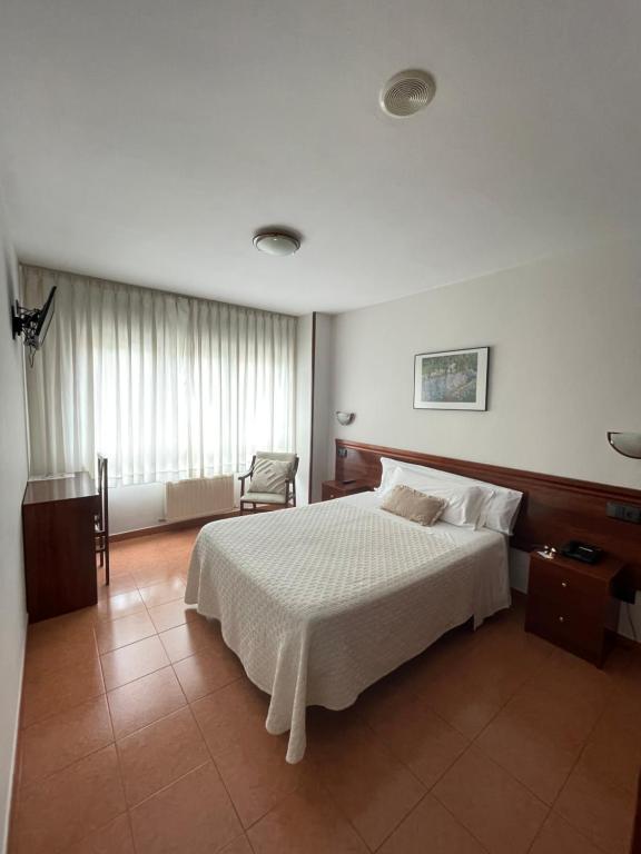 a bedroom with a large white bed and a chair at Hotel Valdés in Gijón