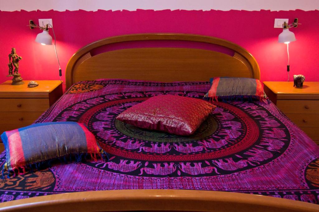 a bedroom with a bed with a pink wall at Laxmi Guesthouse B&B in Genoa
