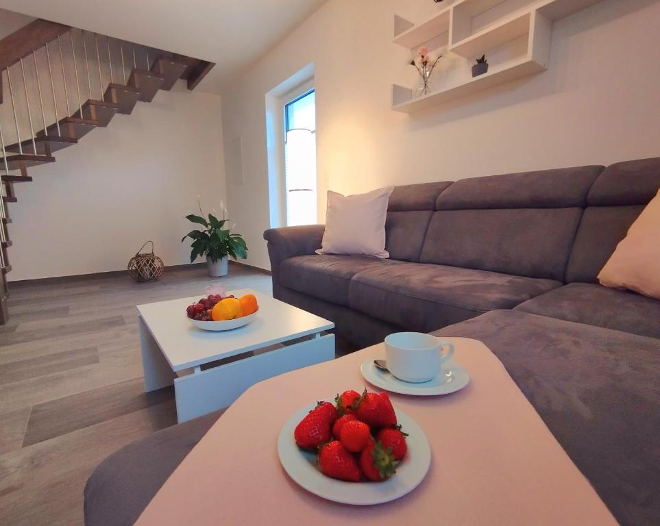 uma sala de estar com um sofá e uma mesa com fruta em Ferienwohnung BlumenMeer em Ostseebad Karlshagen