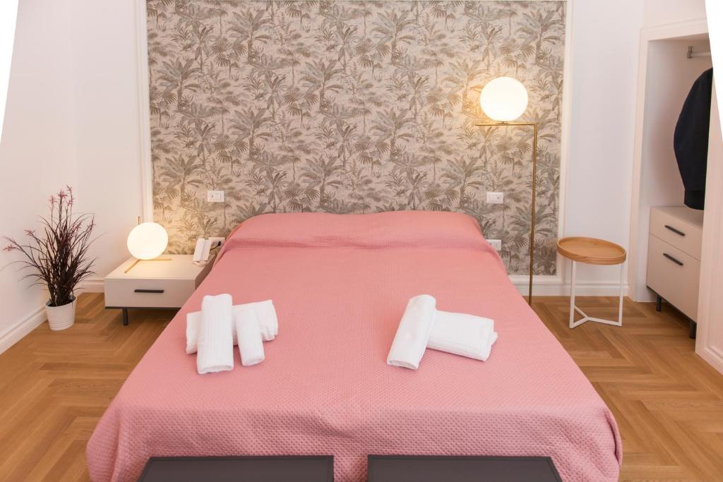 a bedroom with a pink bed with white towels on it at Le Dimore di Puglia - Palazzo Ladogana in Monopoli